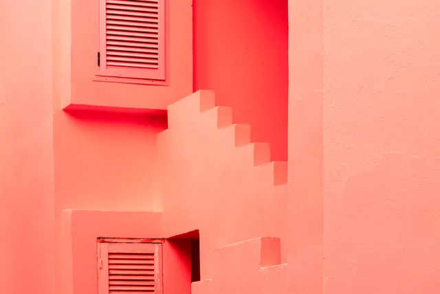 Pink and coral stairways, textured walls, and louvered shutters at La Muralla Roja.
